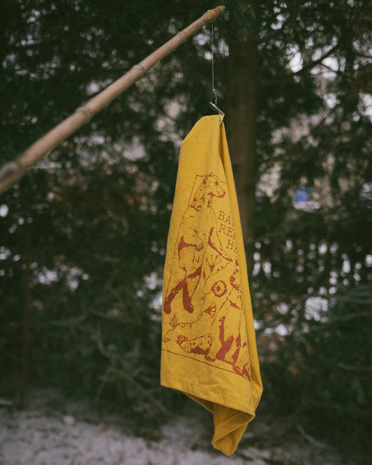 a handmade river cane fishing pole holding a mustard yellow abortion pro choice crop tee shirt in mustard yellow