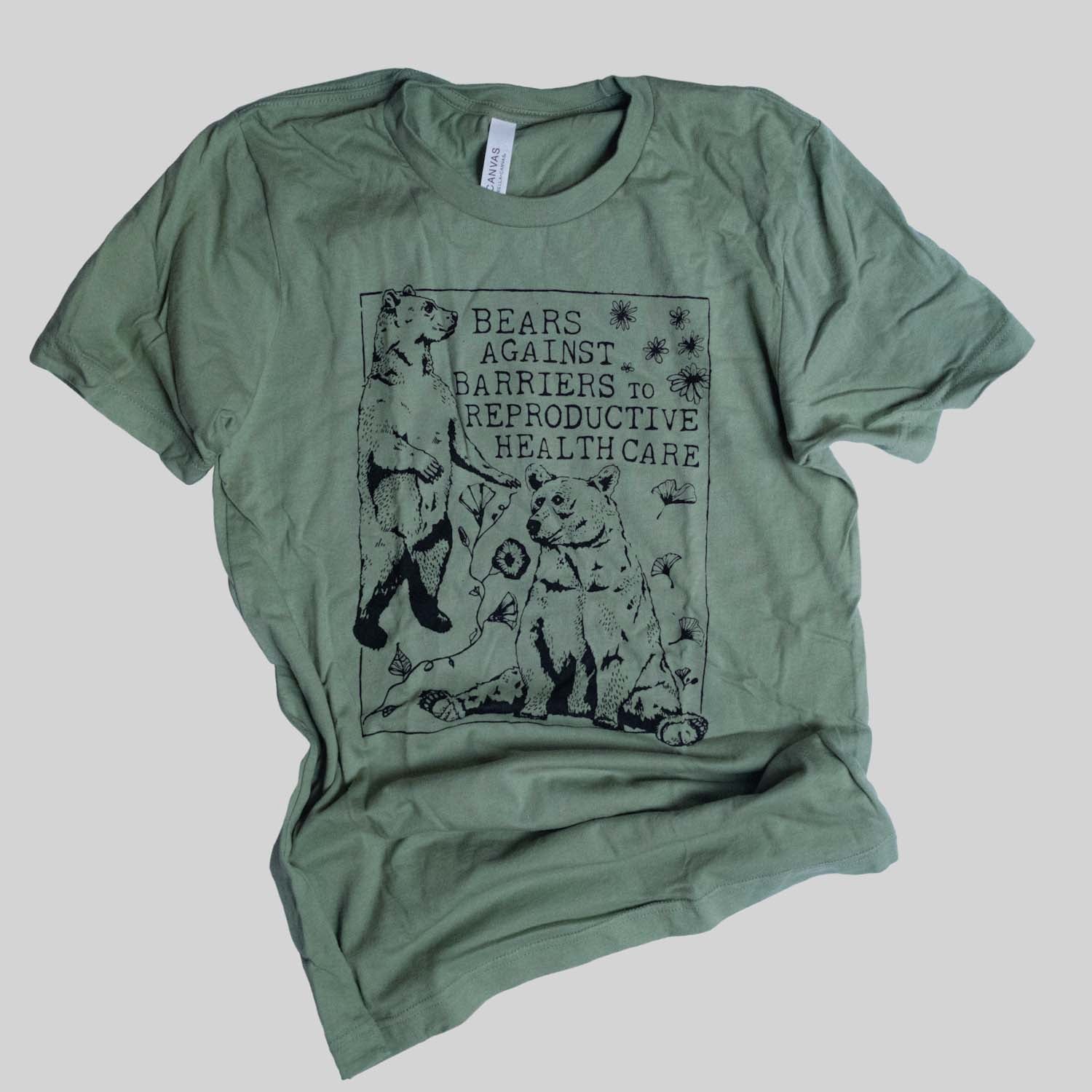 Screen printed feminist soft style green t shirt with illustration of 2 bears, gingko leaves, and flowers with the text Bears Against Barriers to Reproductive Health Care in a serif typeface. ethical and handmade item